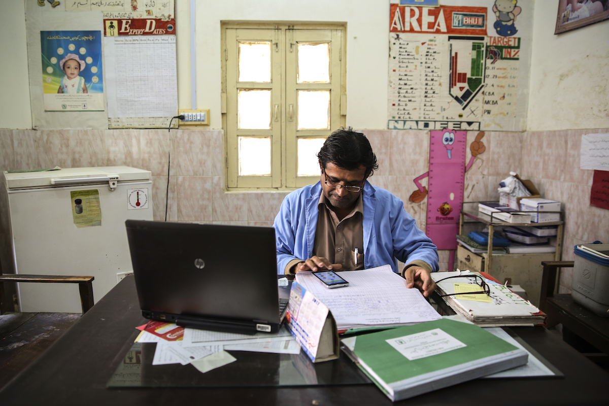 An immunisation worker enters child vaccination data into a mobile app. Hyderabad district, Sindh Province, Pakistan. Photo: WHO/Asad Zaidi